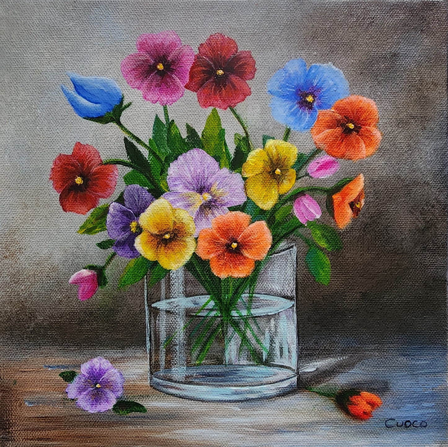 Colorful bouquet of Pansy flowers in a glass vase on a wooden surface with a gray background.