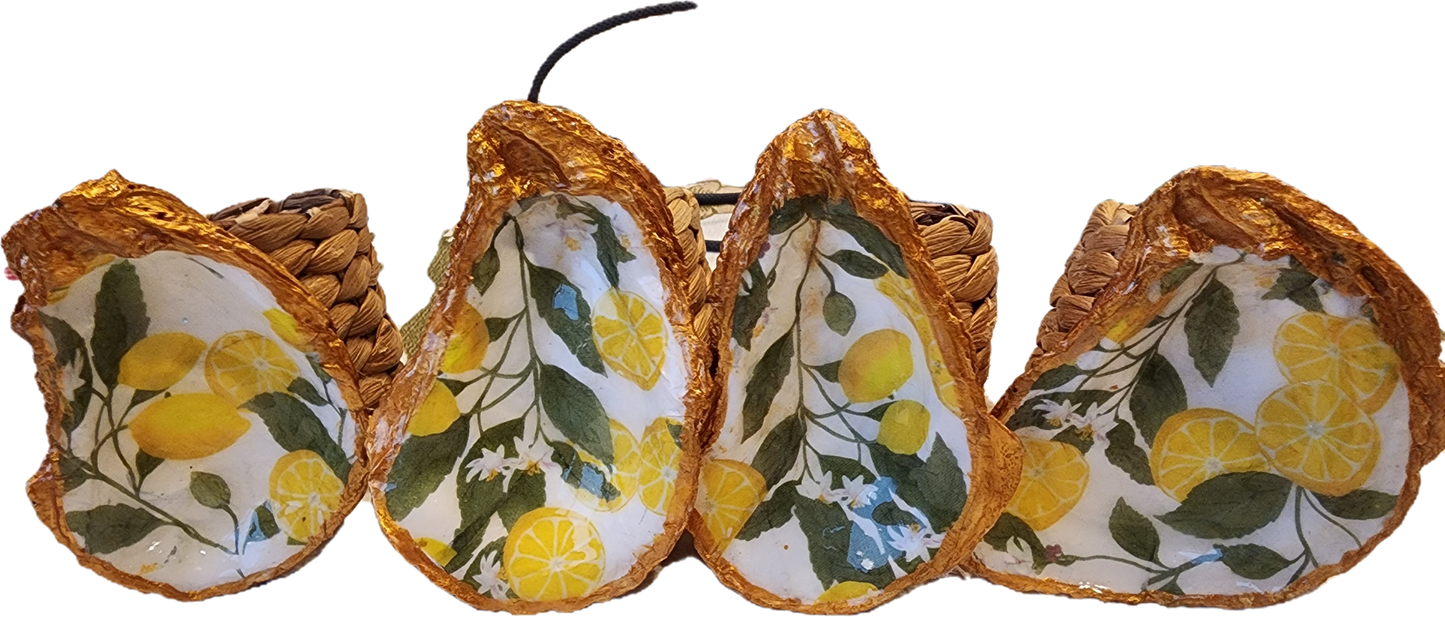 Oyster Shell Napkin Rings with Lemons and leaves on a white background.  The Shell is painted with rich gold around the border and the back of the shell.
